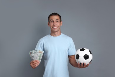 Man with money and soccer ball on grey background