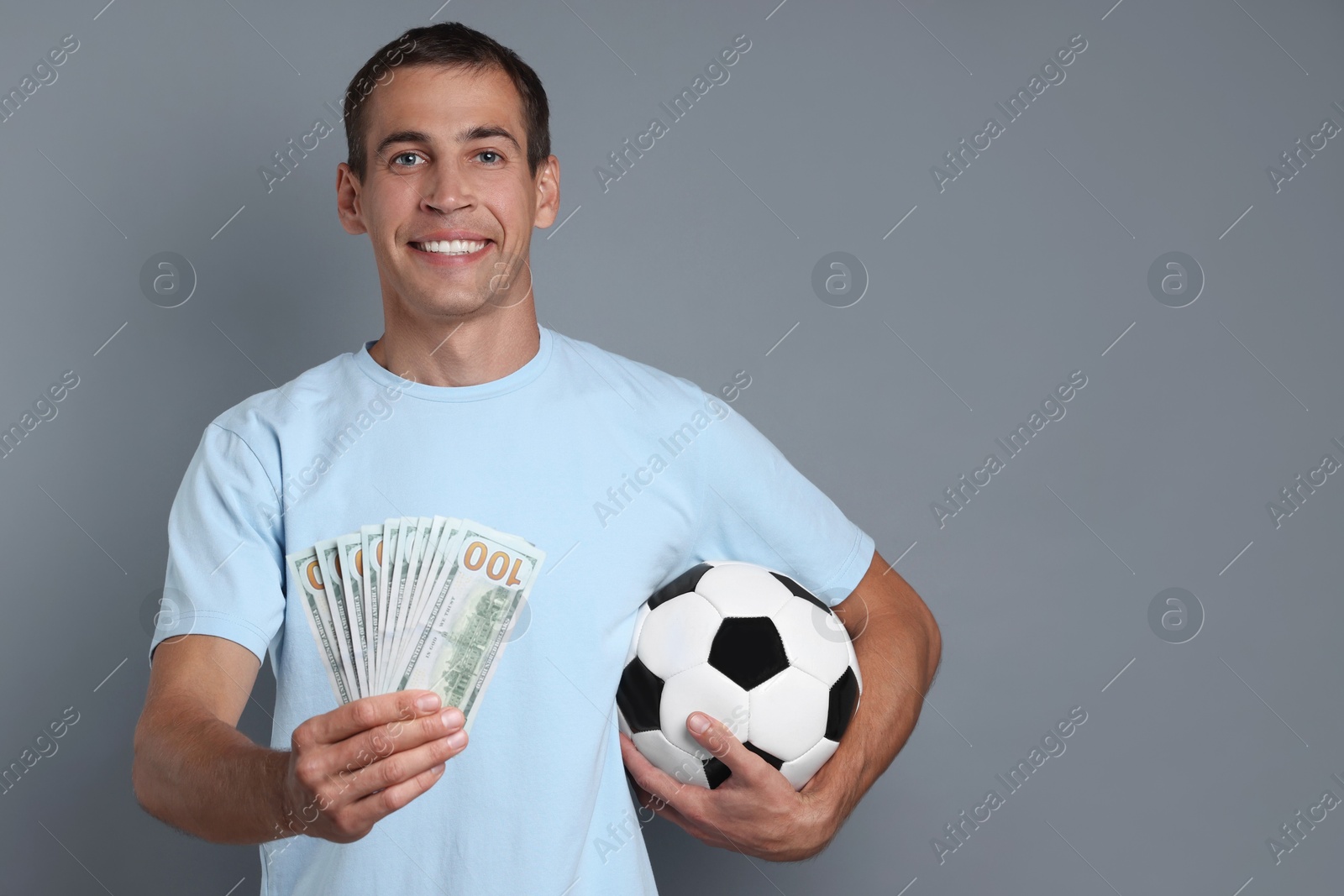 Photo of Man with money and soccer ball on grey background, space for text