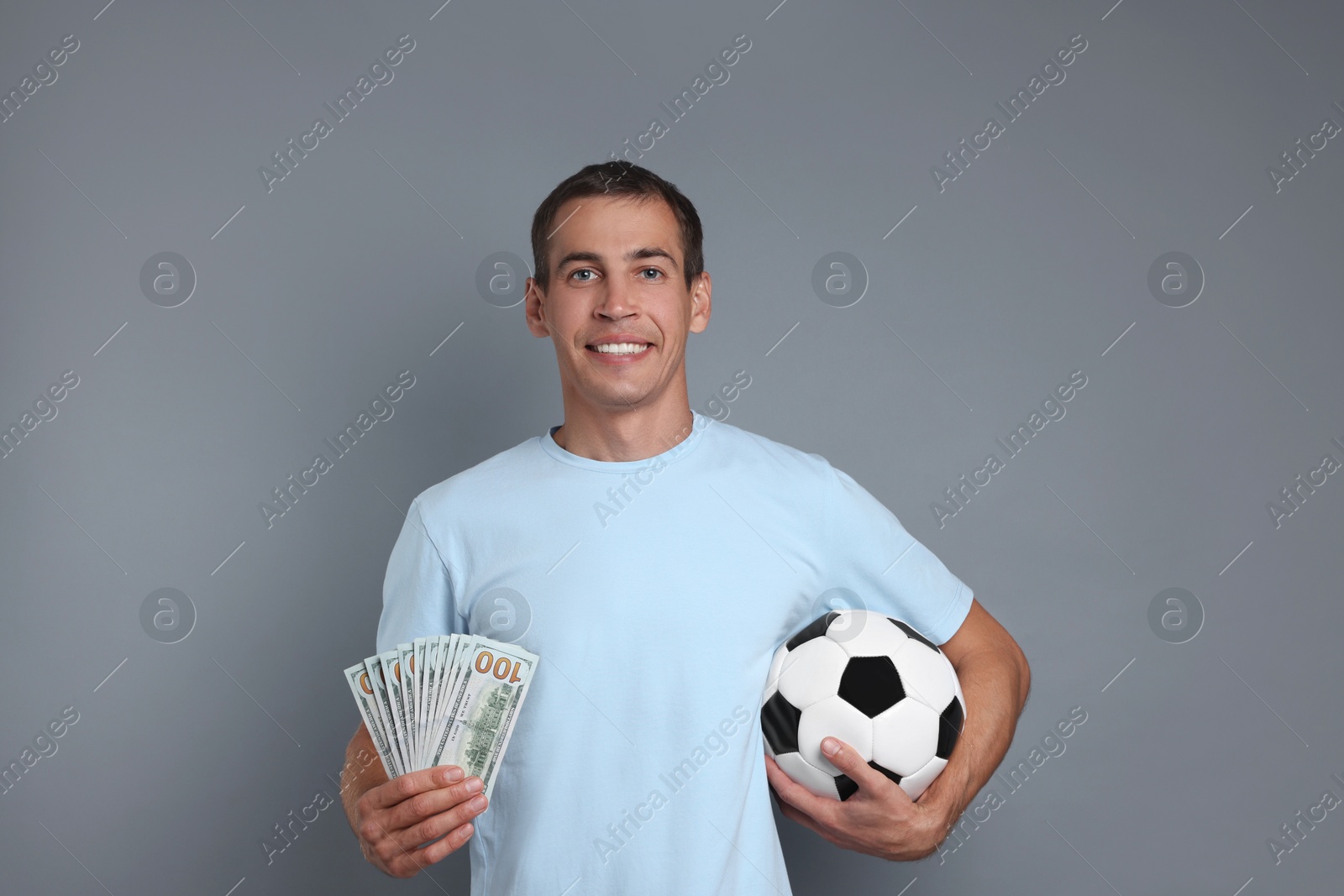 Photo of Man with money and soccer ball on grey background