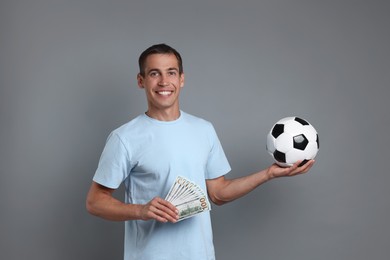 Man with money and soccer ball on grey background