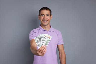 Happy man with money on grey background