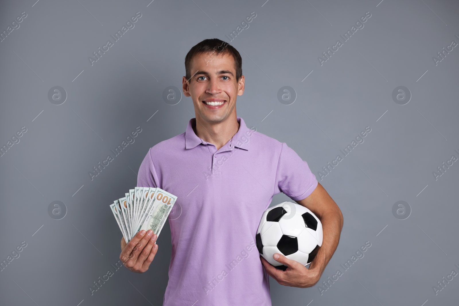 Photo of Man with money and soccer ball on grey background