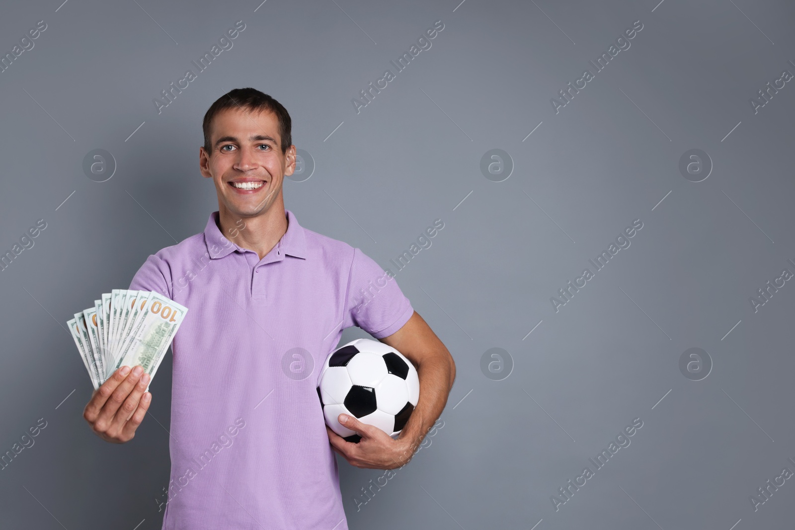 Photo of Man with money and soccer ball on grey background, space for text