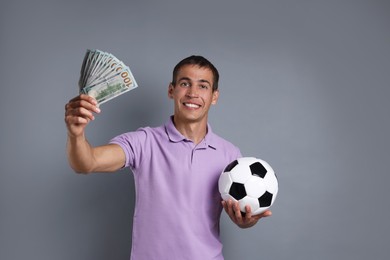 Man with money and soccer ball on grey background