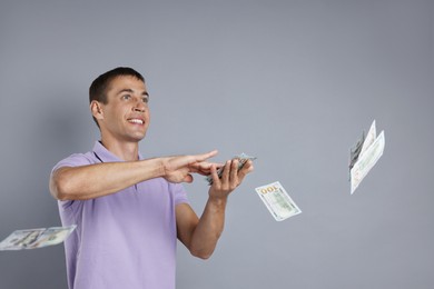 Happy man throwing money on grey background