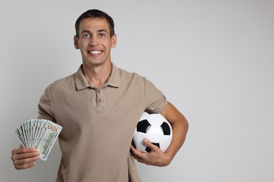 Happy man with money and soccer ball on white background