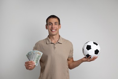 Photo of Happy man with money and soccer ball on white background