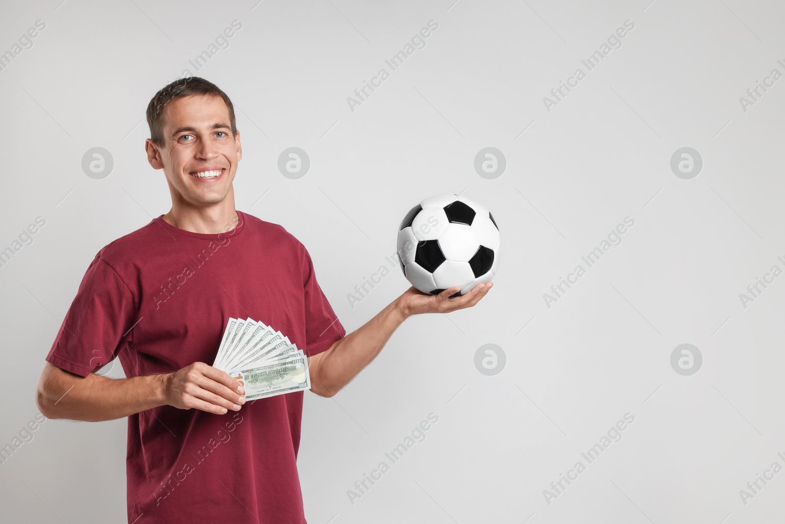 Photo of Happy man with money and soccer ball on white background, space for text