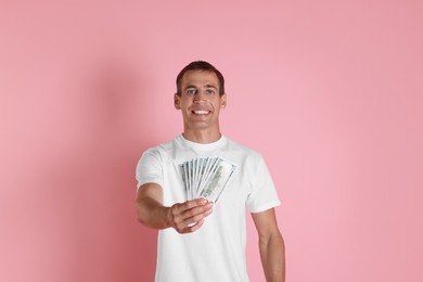 Happy man with money on pink background