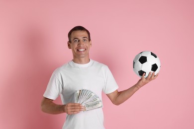 Happy man with money and soccer ball on pink background