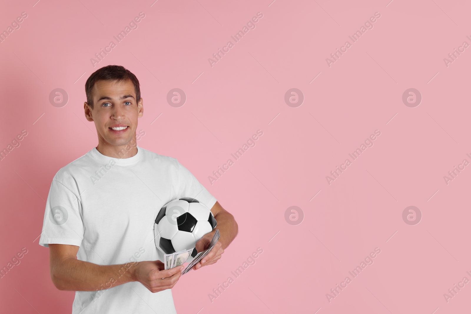 Photo of Happy man with money and soccer ball on pink background, space for text