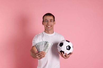 Happy man with money and soccer ball on pink background