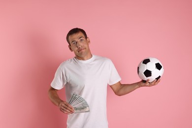 Man with money and soccer ball on pink background