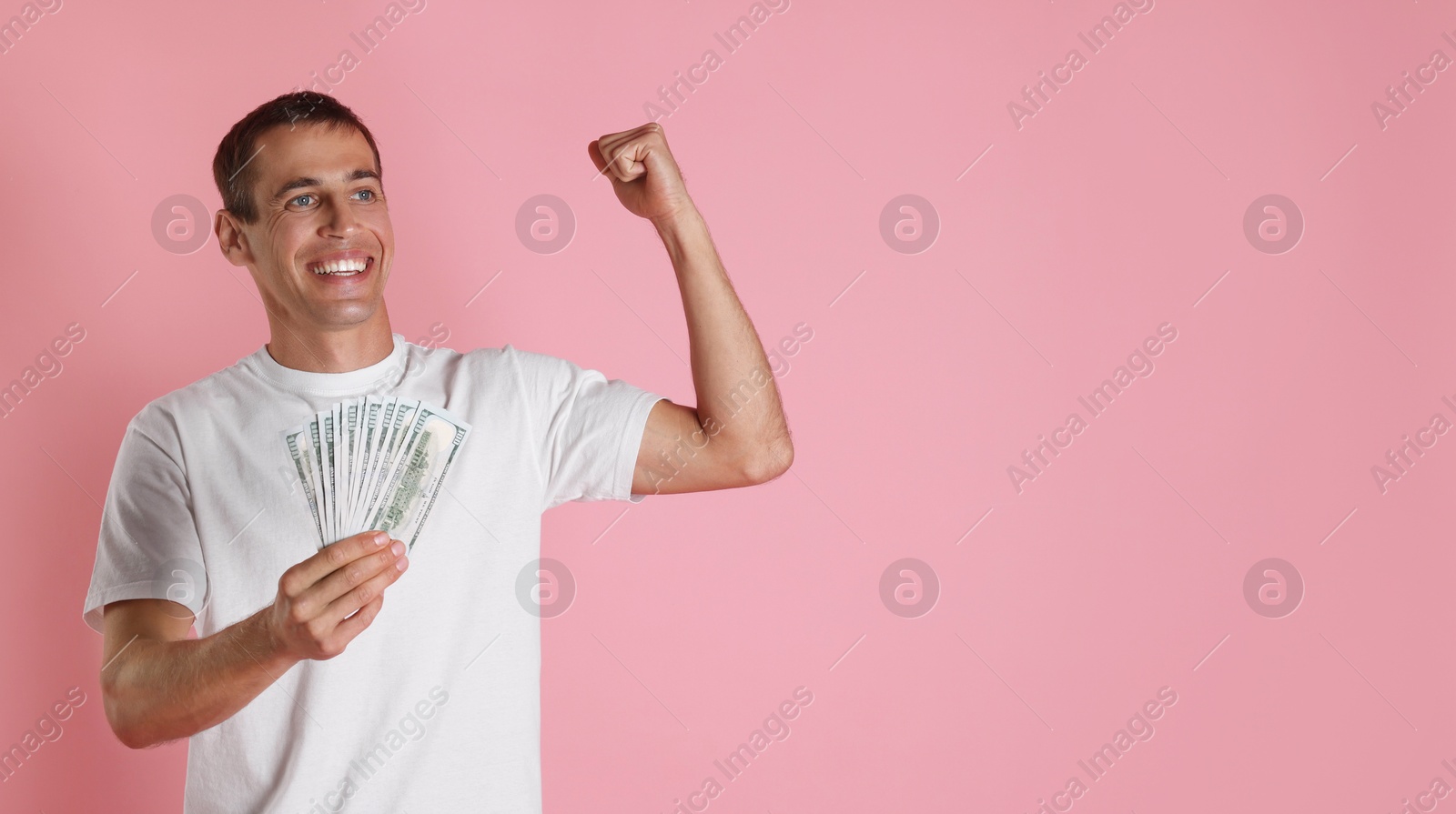 Photo of Happy man with money on pink background, space for text