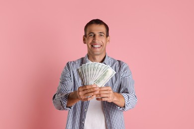 Happy man with money on pink background