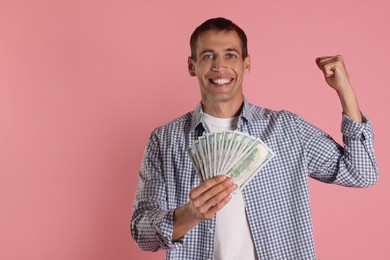 Happy man with money on pink background, space for text