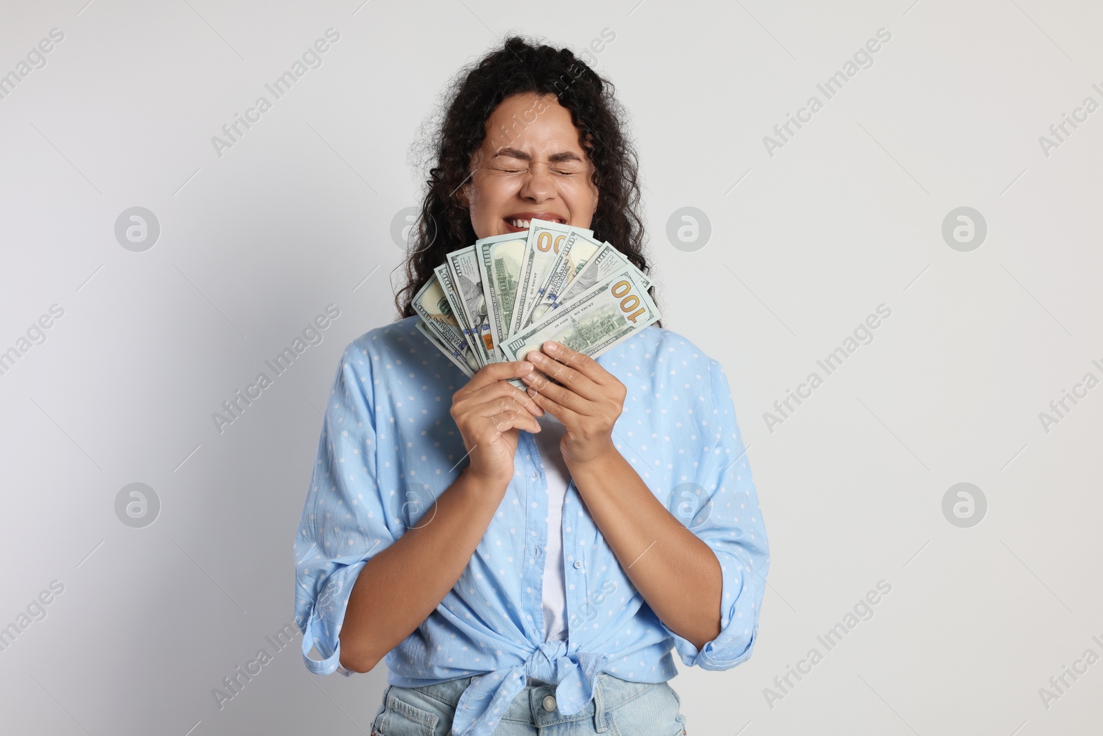 Photo of Happy woman with dollar banknotes on light grey background