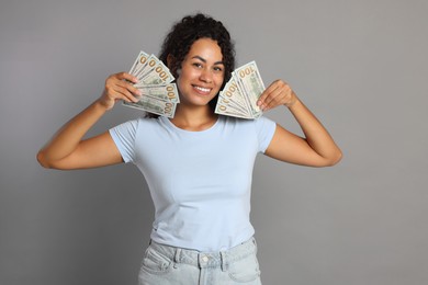 Happy woman with dollar banknotes on grey background