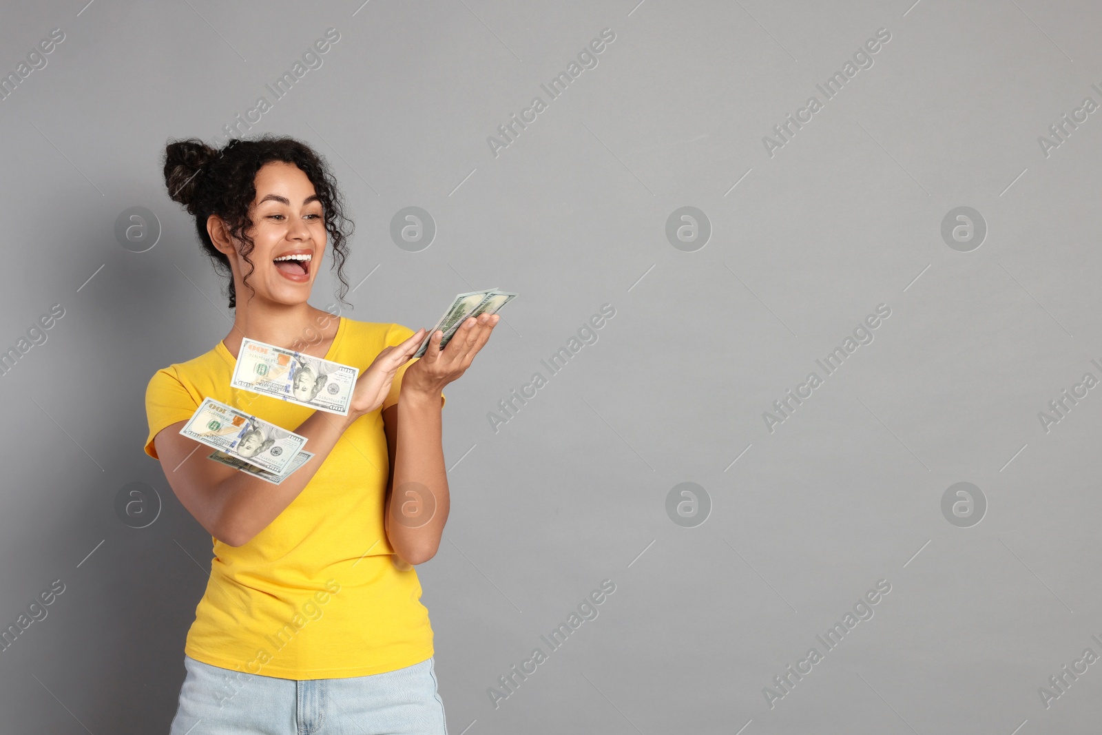 Photo of Happy woman throwing money on light grey background, space for text