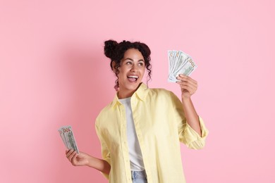 Happy woman with dollar banknotes on pink background