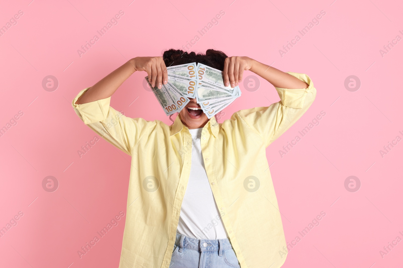 Photo of Woman covering eyes with dollar banknotes on pink background