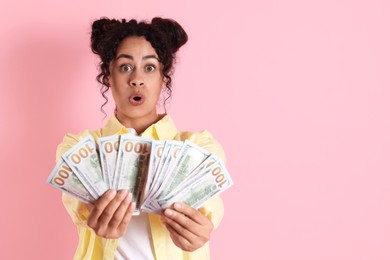 Photo of Shocked woman with dollar banknotes on pink background, space for text