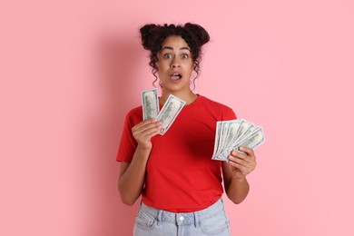 Shocked woman with dollar banknotes on pink background