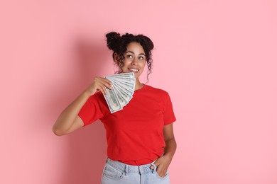 Happy woman with dollar banknotes on pink background