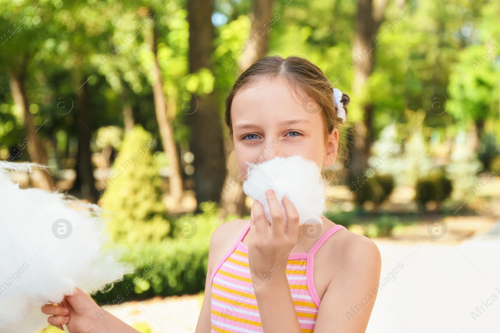 Photo of Portrait of little girl eating sweet cotton candy in park