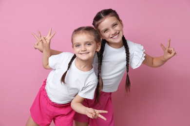 Photo of Portrait of cute little sisters on pink background