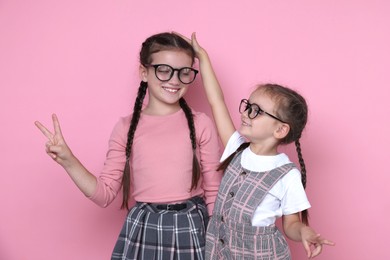 Photo of Portrait of cute little sisters on pink background