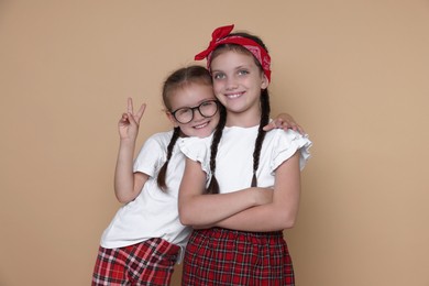 Photo of Portrait of cute little sisters on beige background