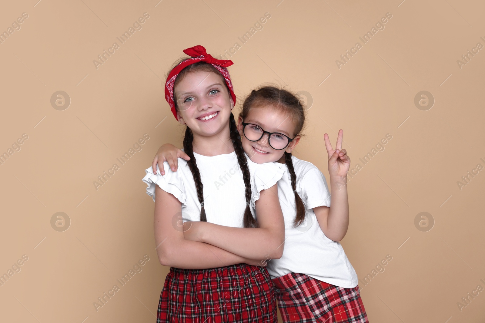 Photo of Portrait of cute little sisters on beige background