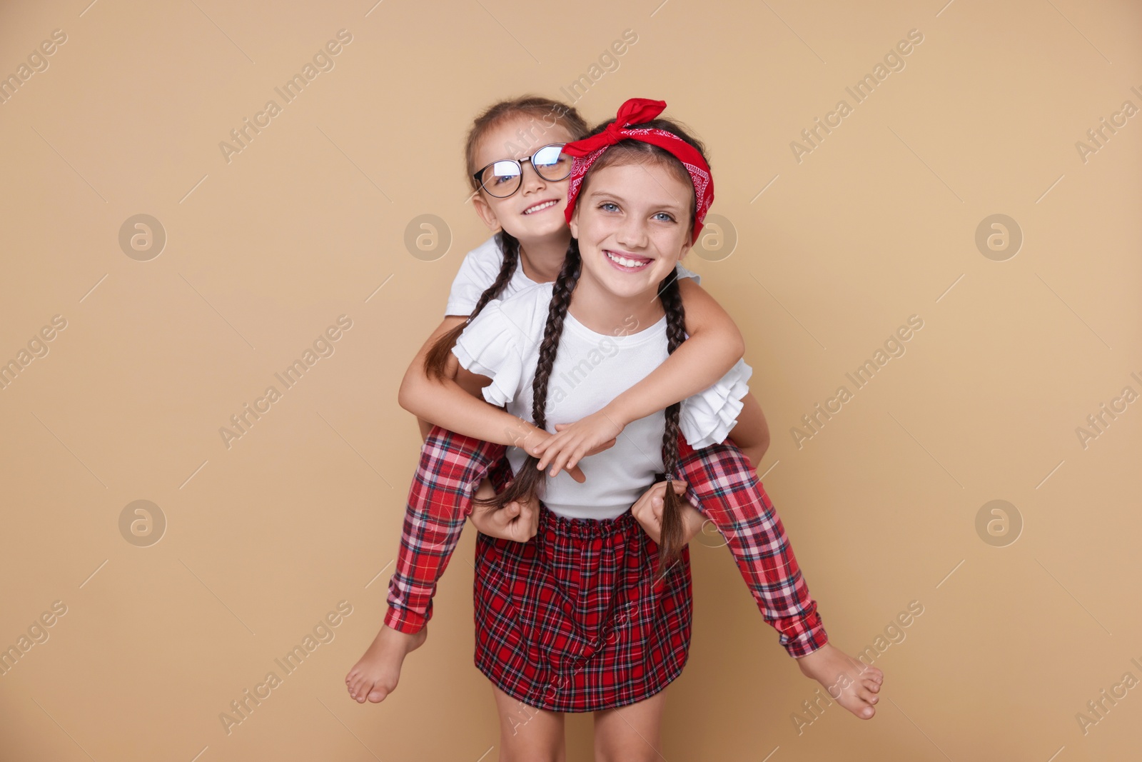 Photo of Portrait of cute little sisters on beige background