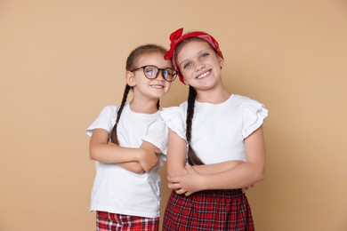 Photo of Portrait of cute little sisters on beige background