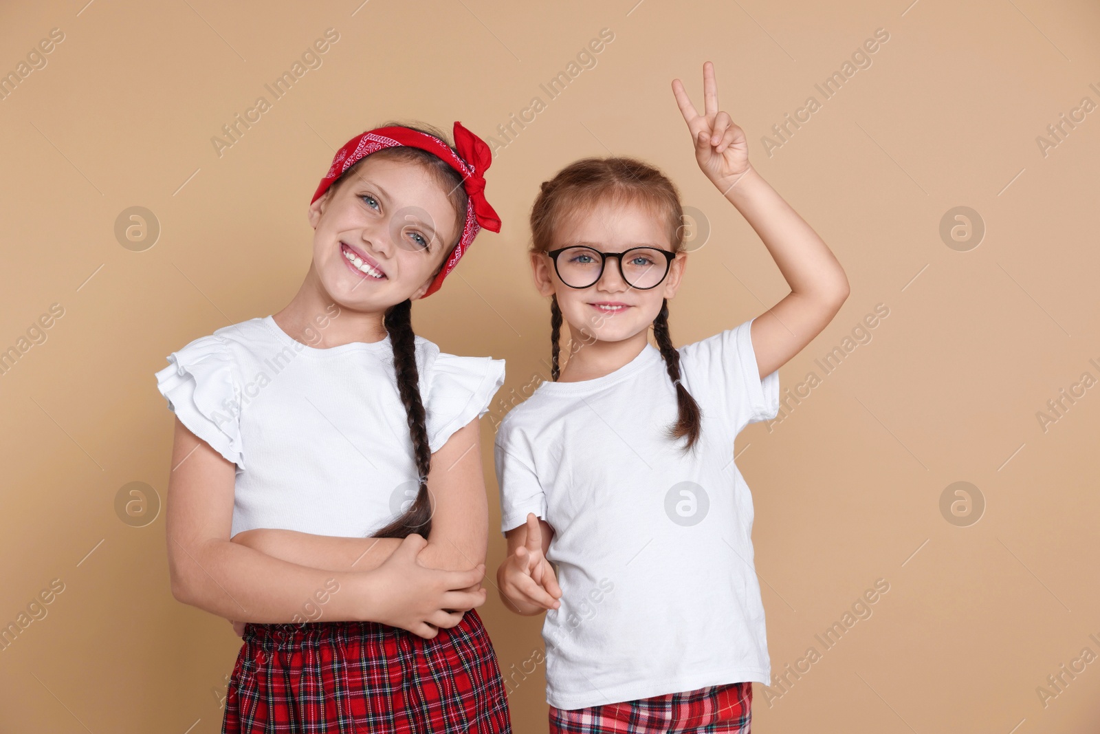 Photo of Portrait of cute little sisters on beige background