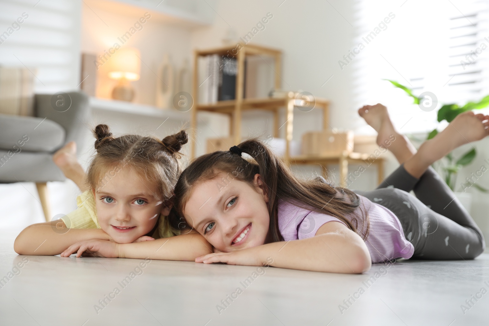 Photo of Cute little sisters spending time together at home