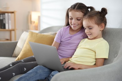 Photo of Cute little sisters with laptop spending time together at home