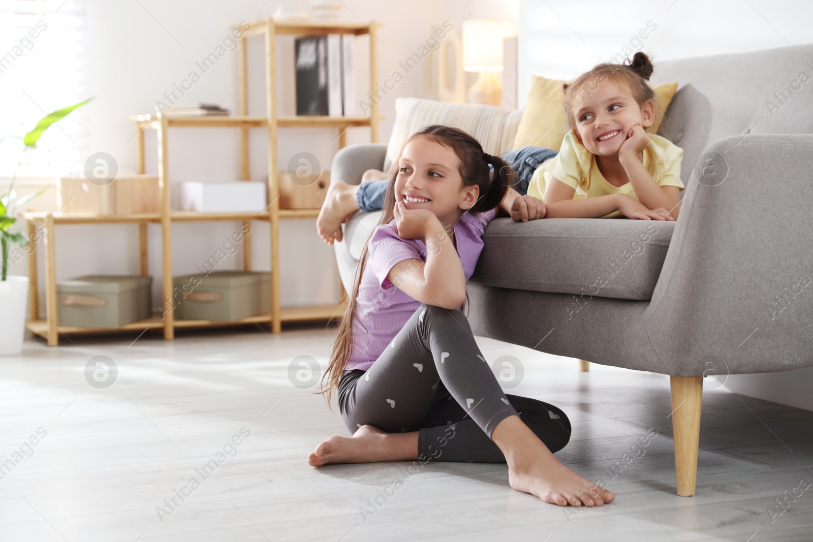 Photo of Cute little sisters spending time together at home, space for text