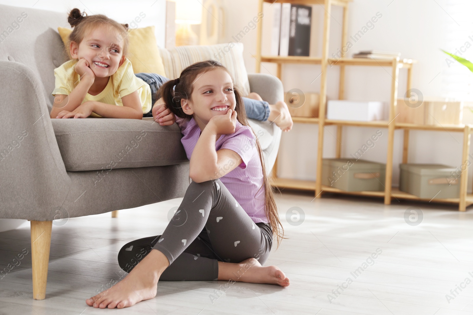 Photo of Cute little sisters spending time together at home, space for text