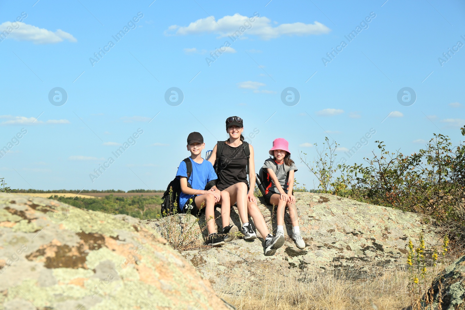 Photo of Cute family enjoying picturesque landscape on stone