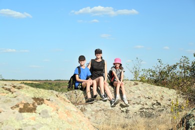 Photo of Cute family enjoying picturesque landscape on stone