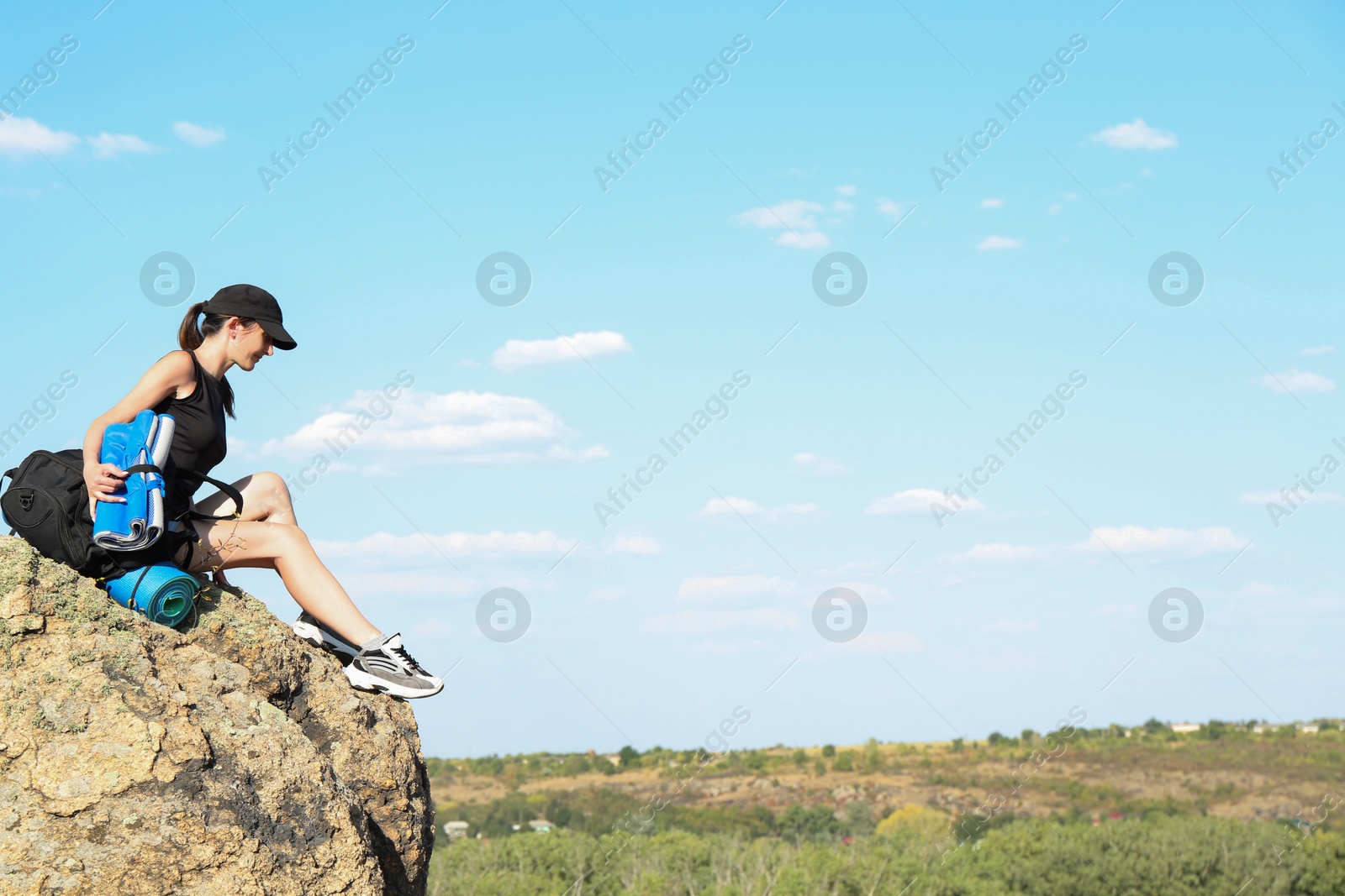 Photo of Beautiful woman enjoying picturesque landscape on stone under blue sky. Space for text