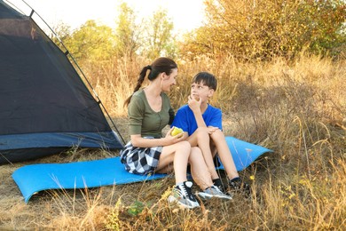 Photo of Mother and son eating apples near camping tent