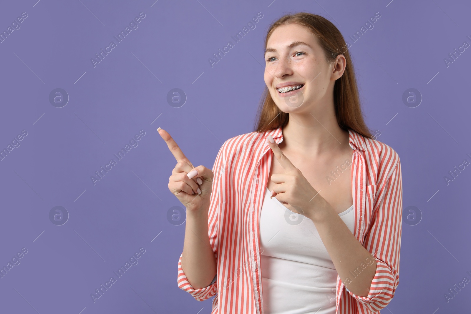 Photo of Smiling girl with braces on purple background, space for text