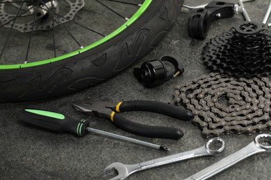 Photo of Parts of bicycle and tools on grey background, closeup