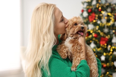 Woman with cute Maltipoo dog in room decorated for Christmas