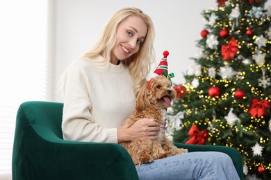 Photo of Woman with cute Maltipoo dog in room decorated for Christmas