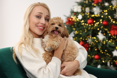 Photo of Woman with cute Maltipoo dog in room decorated for Christmas