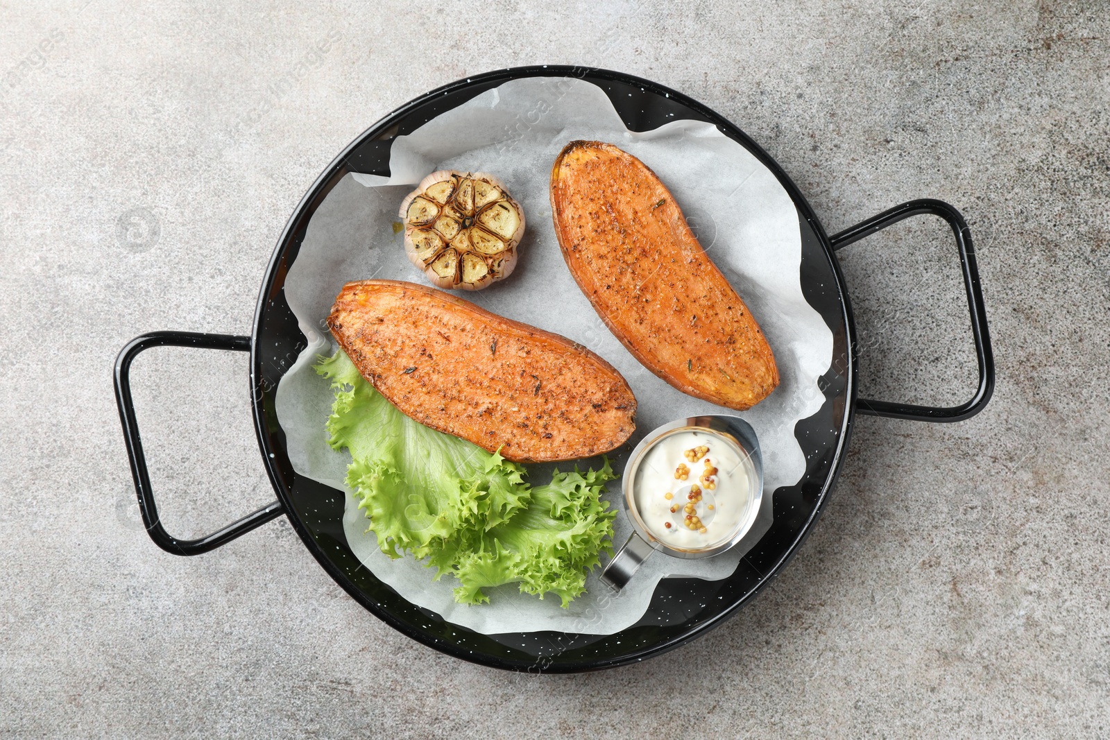 Photo of Tasty cooked sweet potato served in baking dish on grey textured table, top view